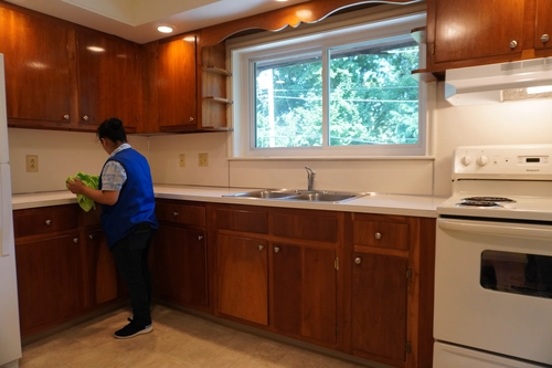 Cleaner tidying a bright apartment kitchen for satisfied tenants