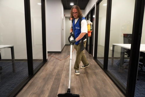Cleaner vacuuming an office hallway during deep cleaning