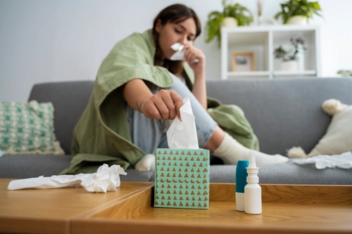 Employee blowing her nose, struggling with workplace allergy symptoms
