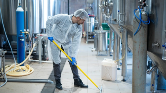 Custodial technician cleaning the floor of a large industrial facility