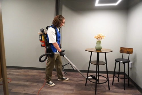 Vacuuming the floor beneath a breakroom table as a checklist task