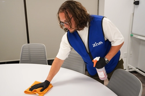 Cleaner wiping down a surface in a tidy office breakroom