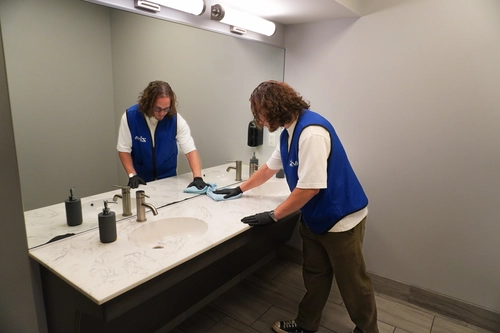 Disinfecting an office restroom sink to cut down on workplace germs