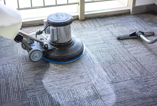 Technician deep cleaning commercial carpet during scheduled maintenance work