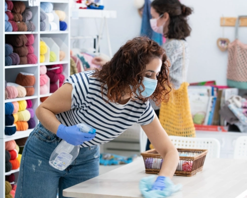 Staff disinfecting a high-touch counter surface in a shop