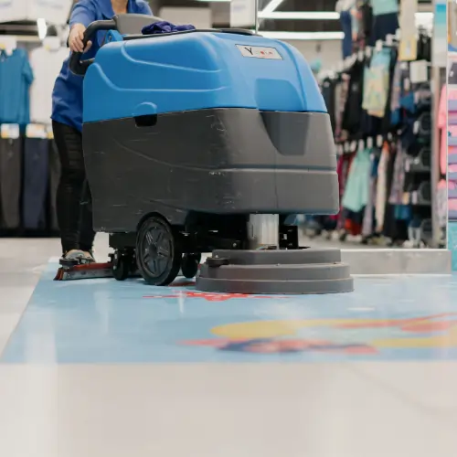 A retail day porter sanitizing high-touch surfaces on the sales floor during business hours