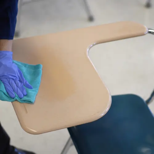 Wiping down a classroom table to a spotless finish
