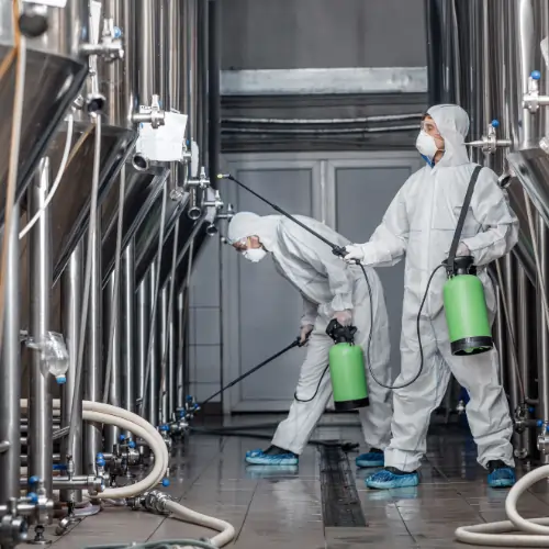 Technician deep-cleaning factory machinery and floors during a service