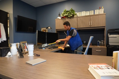 Cleaner dusting an office desk to keep the workspace spotless