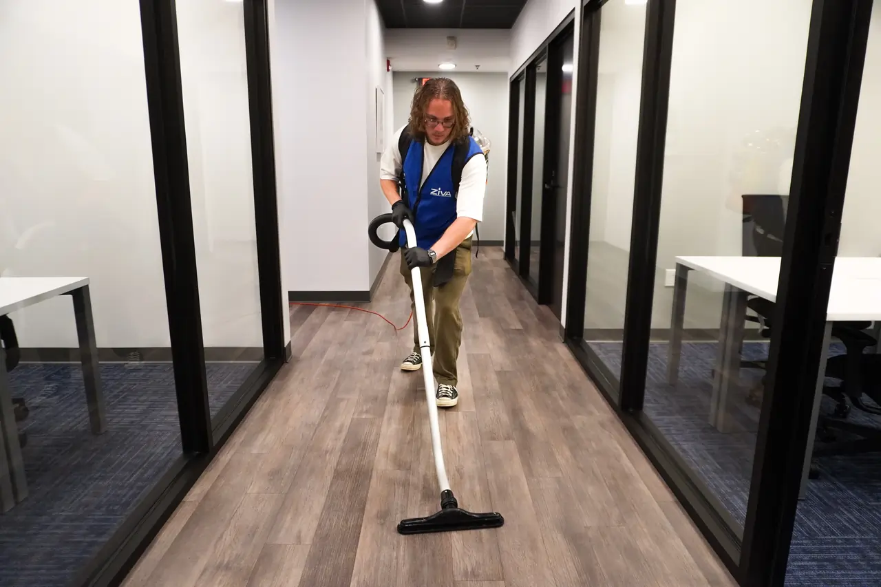 Cleaner vacuuming an office hallway during routine commercial cleaning